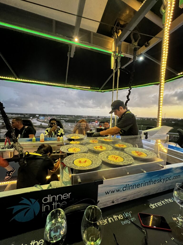 Chef plating dishes aboard Dinner in the Sky platform at dusk in Punta Cana