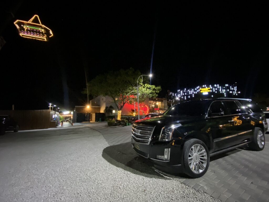 Black Cadillac Escalade parked at night near a lit bar in Punta Cana