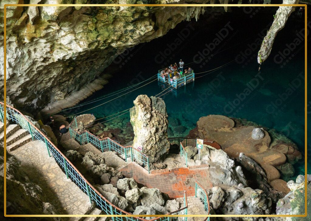 Tourists on a raft inside Los Tres Ojos cave with turquoise water and walkways