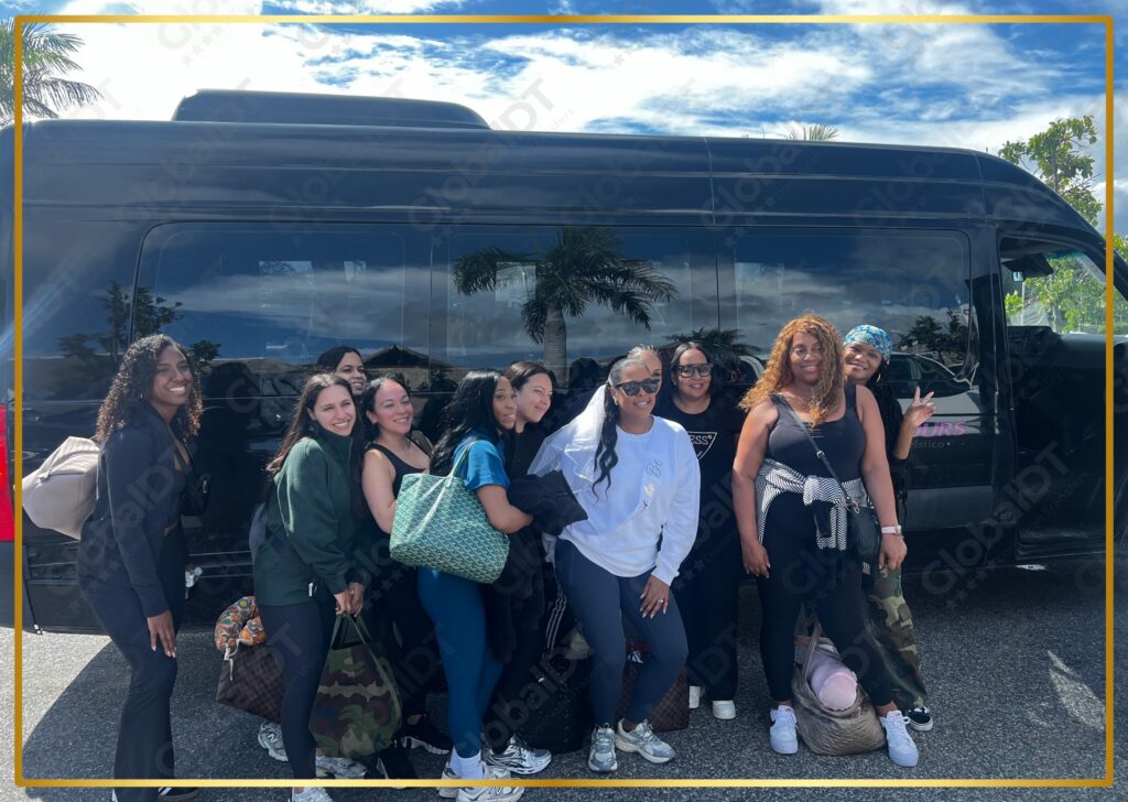 Group of young women posing in front of a black GlobalDT passenger van under a cloudy sky