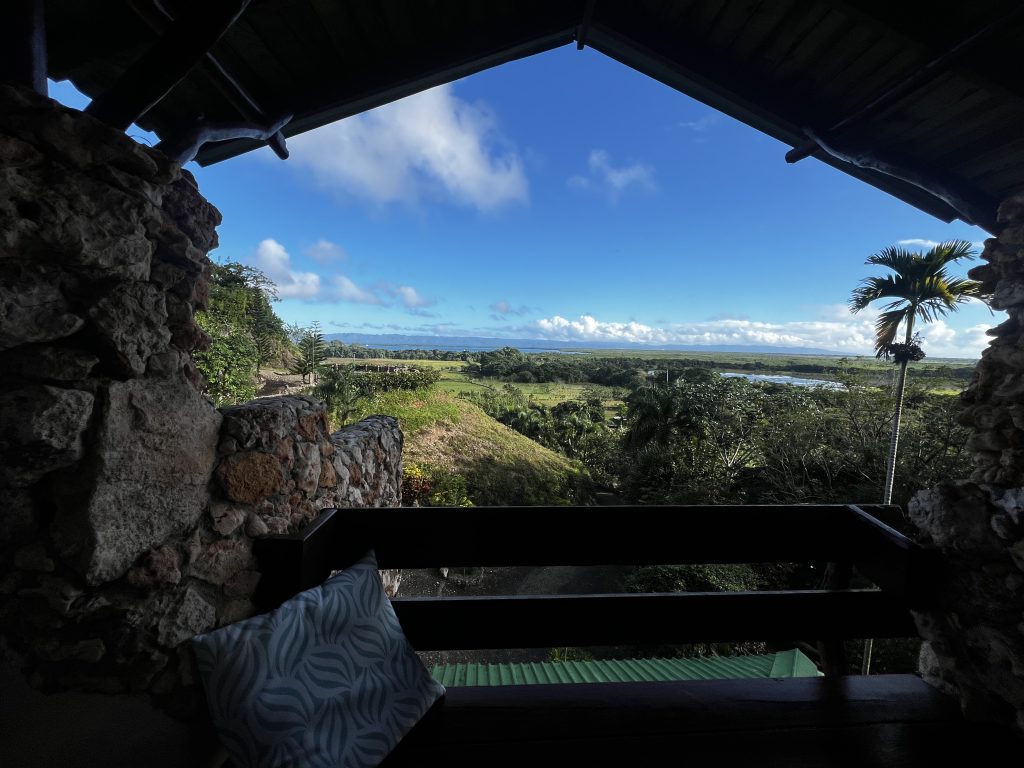 Stone lookout terrace with a bench, overlooking lush tropical landscape and blue sky