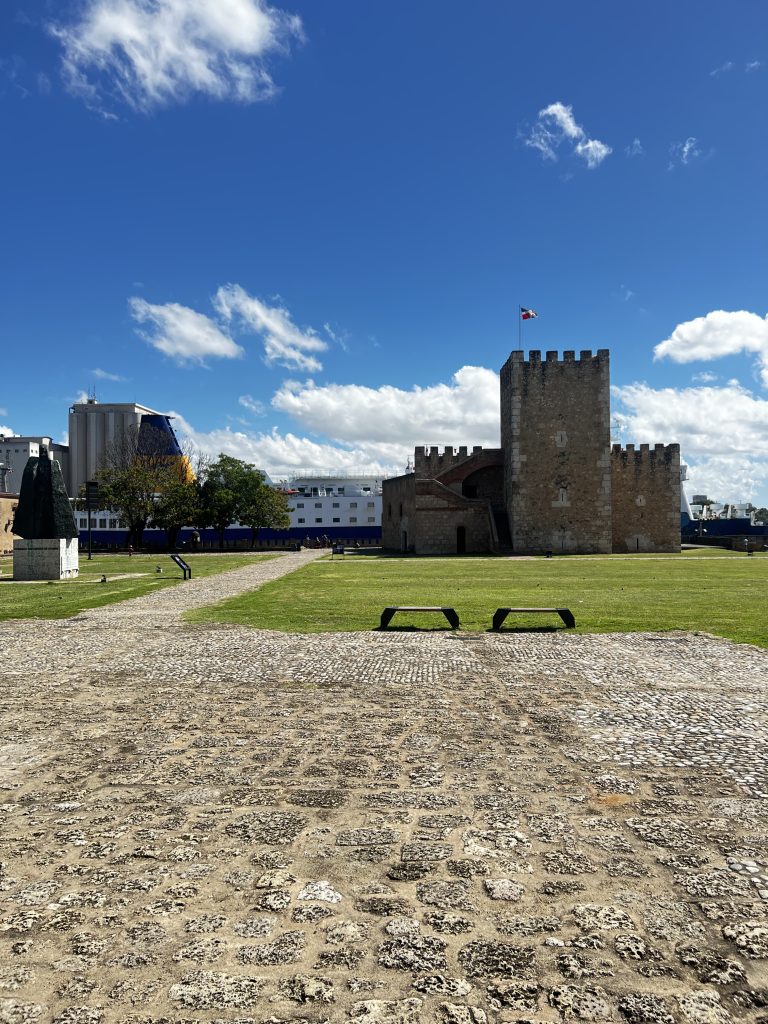 Fortaleza Ozama stone tower and fort with flag under blue sky in Santo Domingo