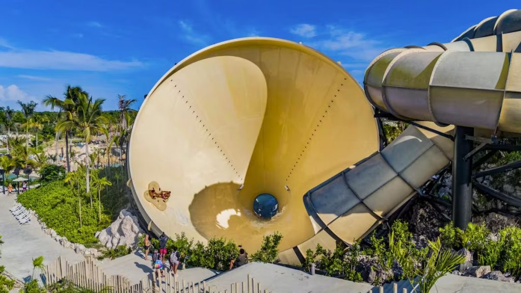 Giant yellow tornado funnel water slide surrounded by palms at a tropical water park