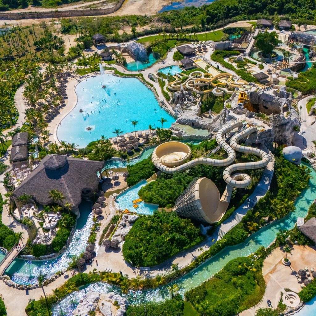 Aerial view of a sprawling tropical water park with pools slides and thatched cabanas