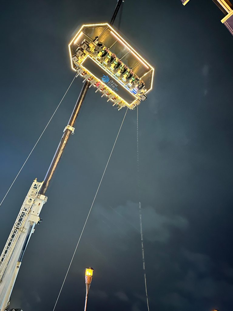 Nighttime ride platform suspended high above the ground, lit by bright perimeter lights